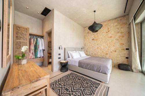 a bedroom with a bed and a stone wall at Lithos Art Villas in Sarlata