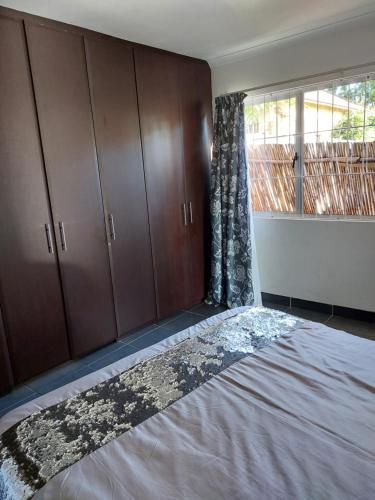 een slaapkamer met een bed, houten kasten en een raam bij Morningview Cottage - Self Catering Private Owned Rental in Durban