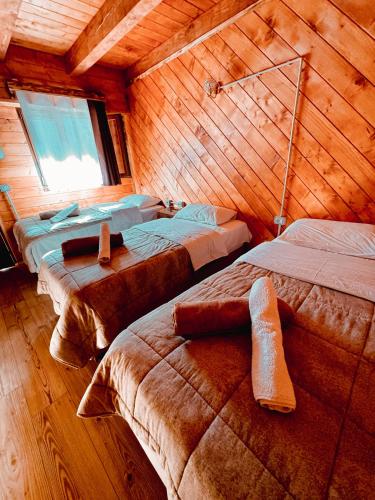 a room with three beds in a wooden cabin at Guesthouse Prrockaj Theth in Theth