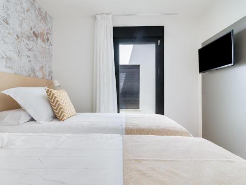 a bedroom with a white bed and a television at Vivelorural Paraíso de Agaete, infinity pool in Agaete