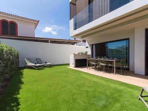 a backyard with green grass and a table and chairs at Vivelorural Paraíso de Agaete, infinity pool in Agaete