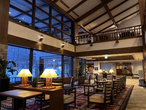 a hotel lobby with tables and chairs and windows at Hakuba Tokyu Hotel in Hakuba