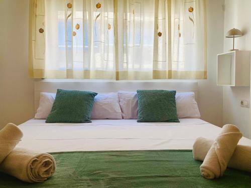 a large white bed with green pillows and a window at Casa Alicia Altea by DelucaCo in Altea
