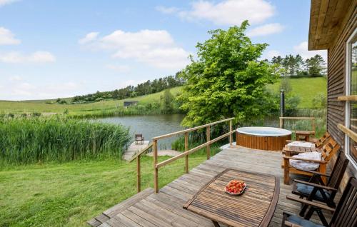 a wooden deck with a table and chairs on a lake at Lovely Home In Ugerløse With Kitchen in Ugerløse