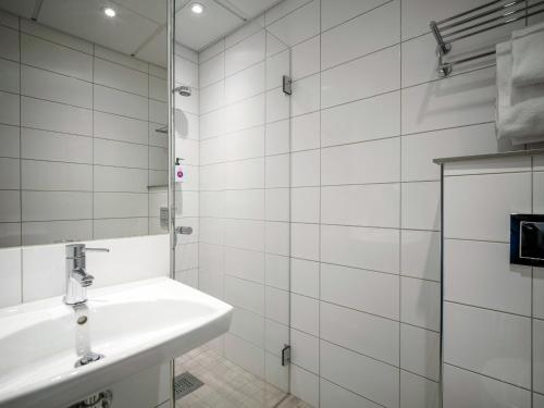 a white bathroom with a sink and a mirror at Quality Hotel Grand Kristiansund in Kristiansund