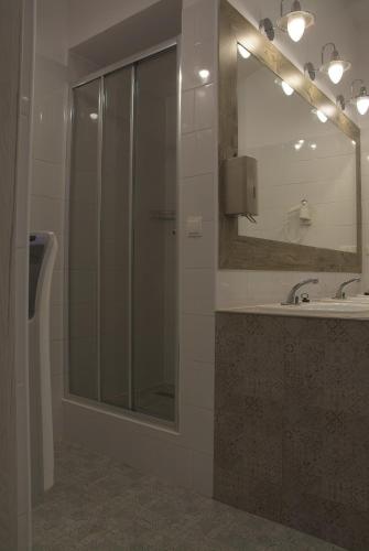 a bathroom with a shower and a sink and a mirror at Hostel Lwowska 11 in Warsaw