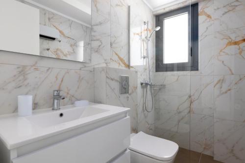 a white bathroom with a sink and a toilet at Aegean Escape Luxury Apartment in Rhodes Town