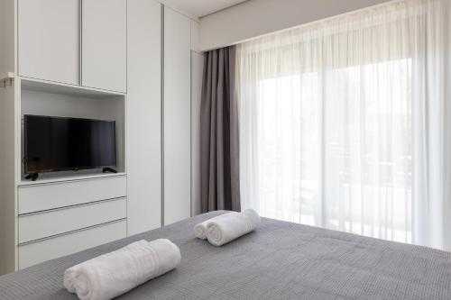 a bedroom with two towels on a bed with a television at Aegean Escape Luxury Apartment in Rhodes Town