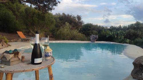 a bottle of wine sitting on a table next to a pool at Stazzu La Piredda in Arzachena