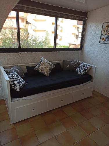 - un canapé avec des oreillers dans une chambre avec une fenêtre dans l'établissement Résidence Sable 4 appartement 5 pers 100 m de la plage, à Leucate