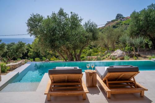 a swimming pool with two lounge chairs next to a swimming pool at Lithos Art Villas in Sarlata