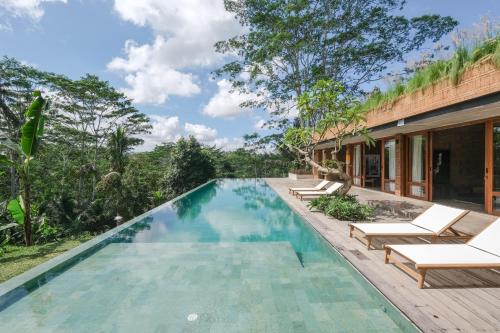 an infinity pool in a villa with chairs and trees at Rumah Subak Tampaksiring in Tampaksiring
