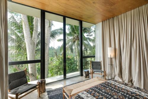 a bedroom with a bed and a large window at Rumah Subak Tampaksiring in Tampaksiring