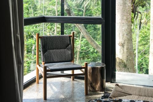 a chair sitting in front of a large window at Rumah Subak Tampaksiring in Tampaksiring