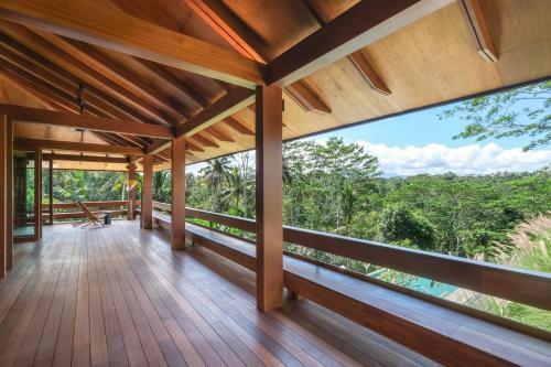 a wooden balcony with a view of the forest at Rumah Subak Tampaksiring in Tampaksiring