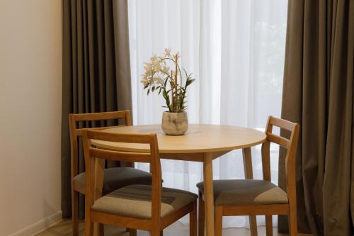 una mesa de madera con 2 sillas y un jarrón con flores en The Journey hotel, en George Town