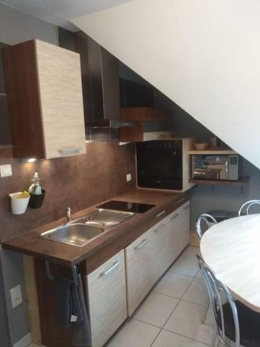 une cuisine avec un évier et un plan de travail dans l'établissement Logement de charme proche Colmar avec terrasse, à Sainte-Croix-en-Plaine