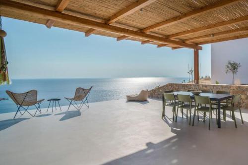 a patio with a table and chairs and the ocean at Infinity View Villa Agios Ioannis Serifos in Serifos Chora