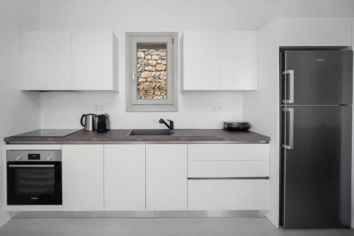 a kitchen with white cabinets and a stainless steel refrigerator at Infinity View Villa Agios Ioannis Serifos in Serifos Chora