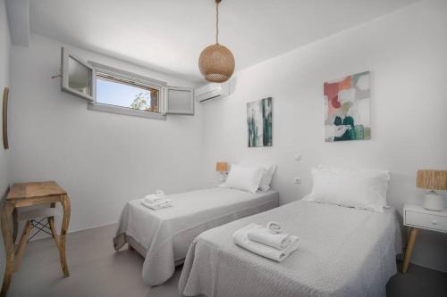 a white room with two beds and a window at Infinity View Villa Agios Ioannis Serifos in Serifos Chora
