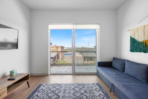 a living room with a couch and a large window at Modern Nulu 2BR CozySuites 02 in Louisville