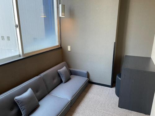 a blue couch in a room with a window at The Centurion Sauna Rest & Stay Sapporo Male Only in Sapporo