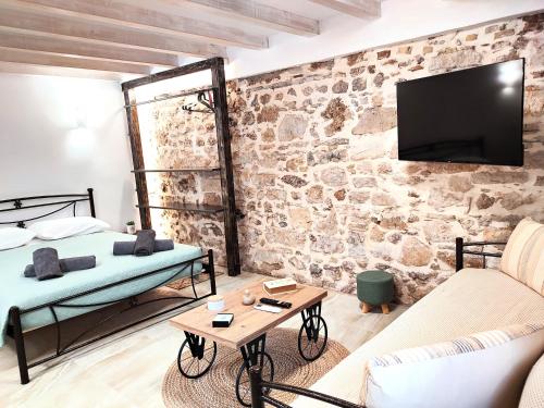a room with two beds and a tv on a stone wall at Akis House Mantouki in Mantoúkion