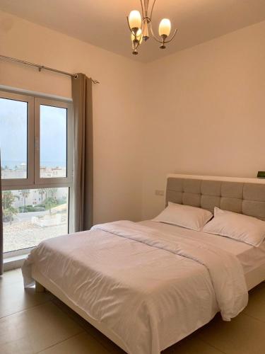 a bedroom with a large bed with a large window at 2BHK furnished flat with jacuzzi in Qantab
