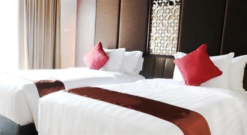 two beds with red pillows in a hotel room at Aston Sentul Lake Resort & Conference Center in Bogor