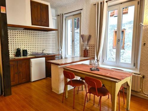 une cuisine avec une table et des chaises dans une cuisine dans l'établissement Appartement Coeur de Cité Vauban Briançon 51m2, à Briançon