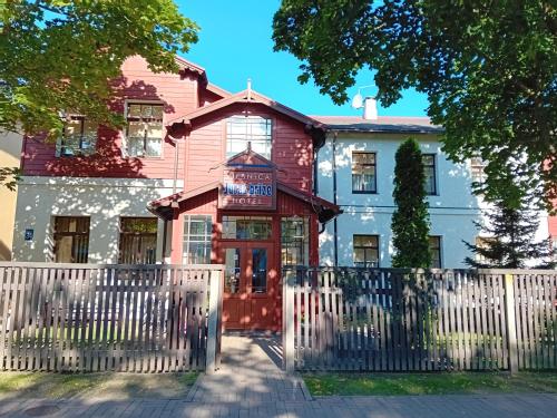 a house with a white fence in front of it at Jūras Brīze in Ventspils