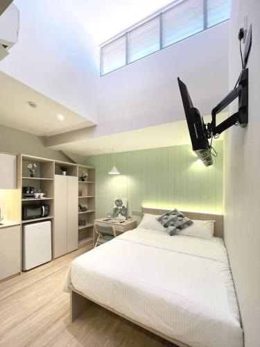 une chambre avec un grand lit blanc et une télévision dans l'établissement Habyt Studios Kallang, à Singapour