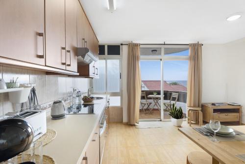 a kitchen with white cabinets and a large window at Vivir Bajamar in Bajamar