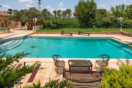 - une grande piscine avec une table et des chaises dans l'établissement Domaine Tombarel, à Brignoles