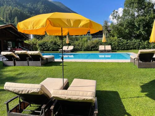 a yellow umbrella and some chairs and a pool at Alpenhotel Tirolerhof in Neustift im Stubaital