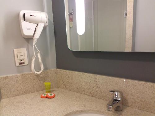 a bathroom sink with a hair dryer and a phone at Ibis Styles Porto Alegre Centro in Porto Alegre