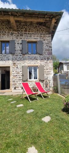 two red chairs sitting in front of a stone house at O Beaujolais Chiroubles in Chiroubles