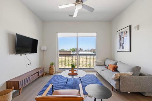 a living room with a couch and a tv at Modern Nulu 2BR CozySuites 06 in Louisville