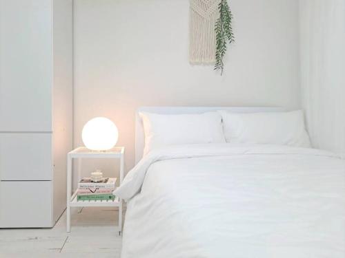 a white bedroom with a white bed and a night stand at HaengGung MaSil in Suwon