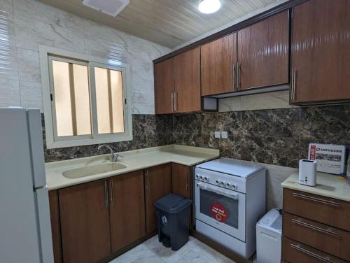 a kitchen with wooden cabinets and a sink and a dishwasher at Wadha Luxury Apartment in Al Khobar