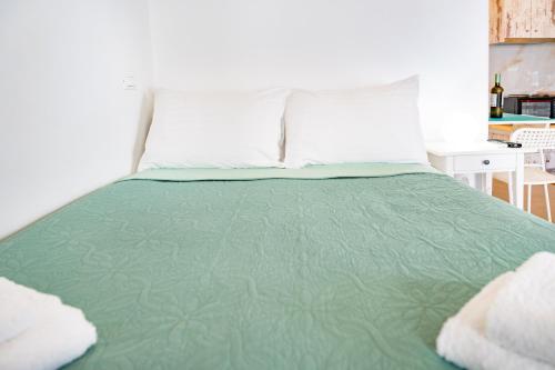 a bed with a green comforter and white pillows at Irene's Studio in Tourlos