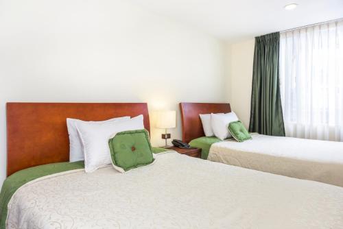 una camera d'albergo con due letti con cuscini verdi di Hotel Portofino a Bogotá