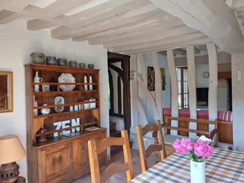 a dining room with a table with a vase of flowers at La Porterie face à l'abbaye in Le Bec-Hellouin