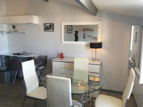 une salle à manger avec une table en verre et des chaises blanches dans l'établissement Studio Vue Port, à La Rochelle