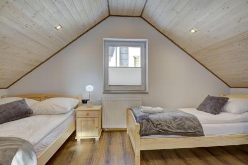 a attic bedroom with two beds and a window at Domki Rynek16 in Tylicz