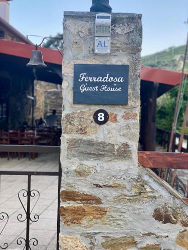 a sign for a guest house on a stone pillar at Ferradosa GuestHouse in São João da Pesqueira