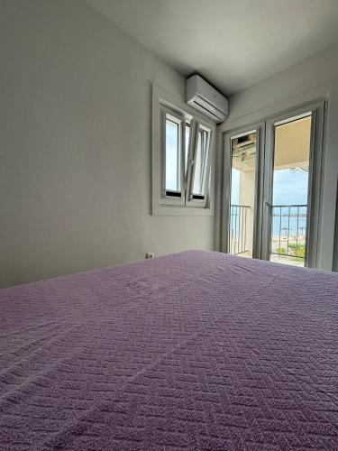 a purple bed in a room with windows at Apartmani Podoreški in Vir