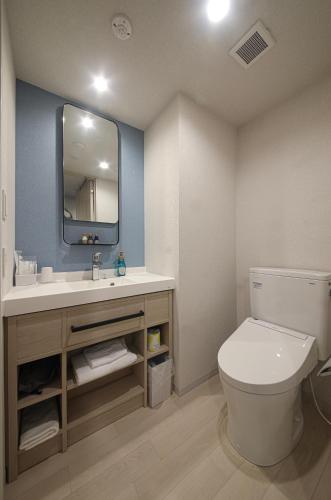 a bathroom with a toilet and a sink with a mirror at Spa World HOTEL&RESORT in Osaka