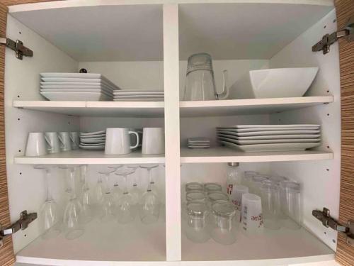 un meuble blanc avec de la vaisselle, des tasses et des assiettes dans l'établissement Jardin d eden village naturiste, au Cap d'Agde