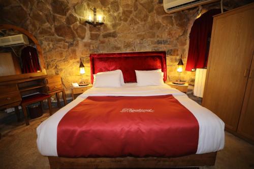 a bedroom with a large bed with a red blanket at Pineland Hotel and Health Resort in Ḩammānā